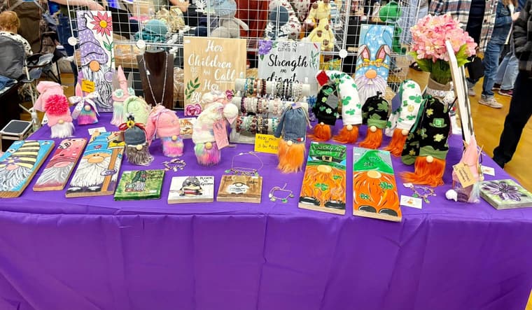 Painted gnome boards, plush gnomes and bracelets at an indoor craft fair